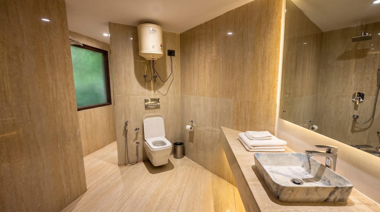 A private bathroom with mirror, counter and folded towels