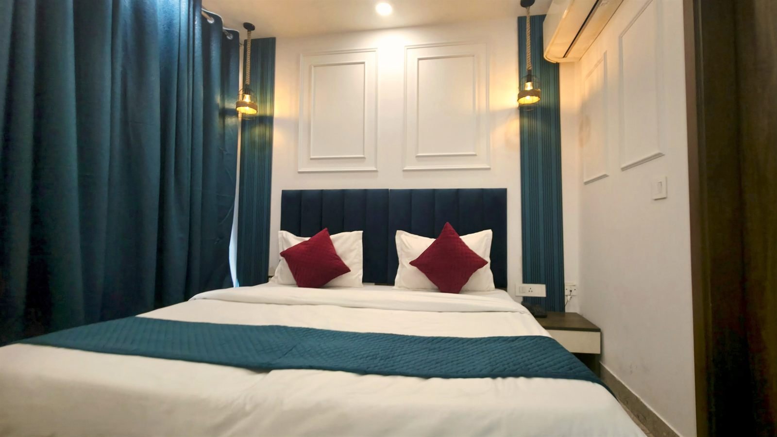 A Deluxe Double made up, navy headboard and framed prints above