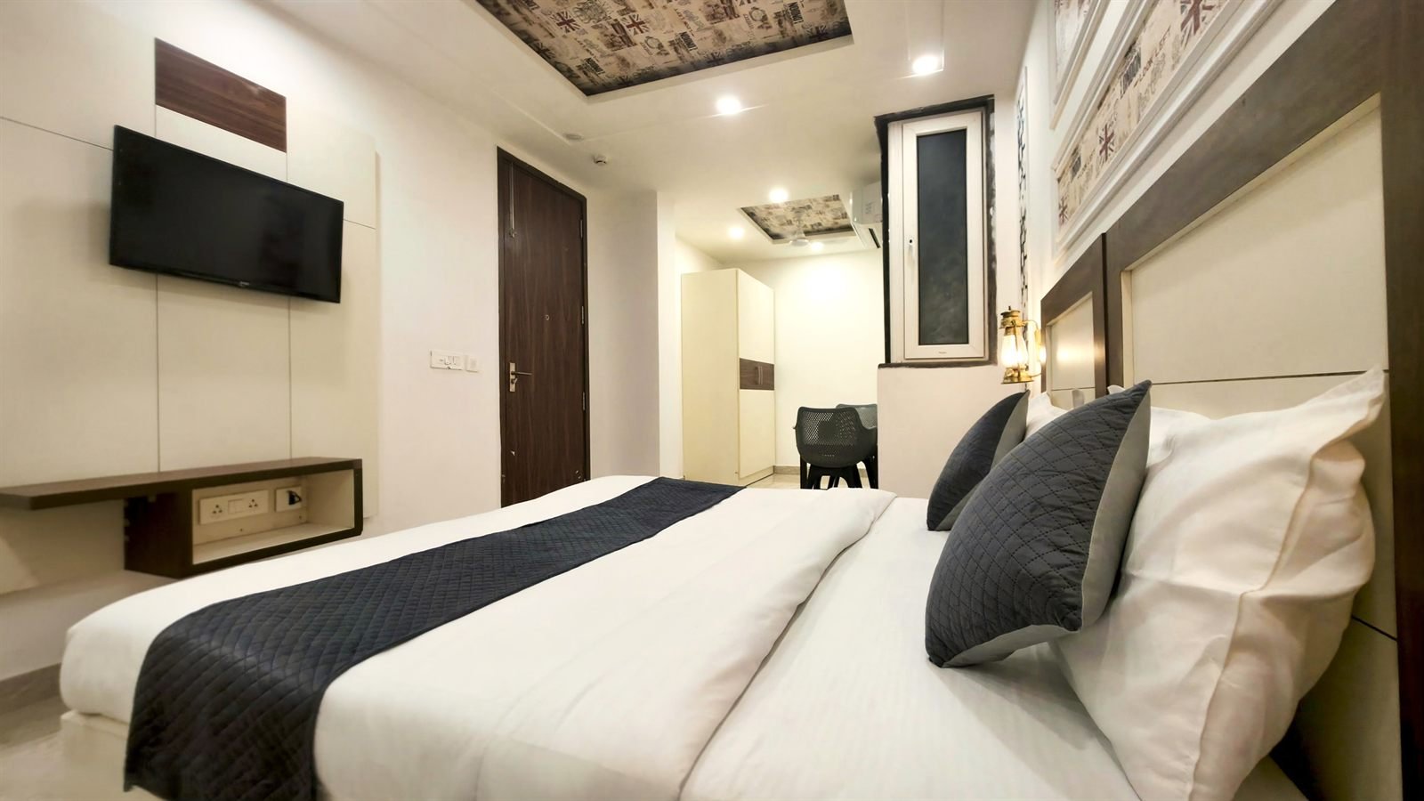 A Deluxe Studio, bed and a desk under a wall lamp