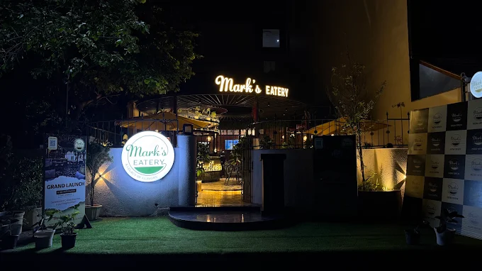 The courtyard after dark, the sign lit above the planting