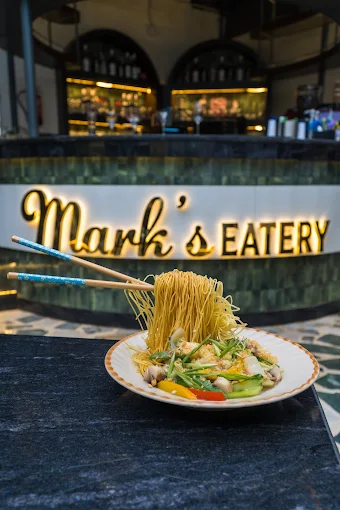 A plate beneath the lit Mark’s Eatery sign