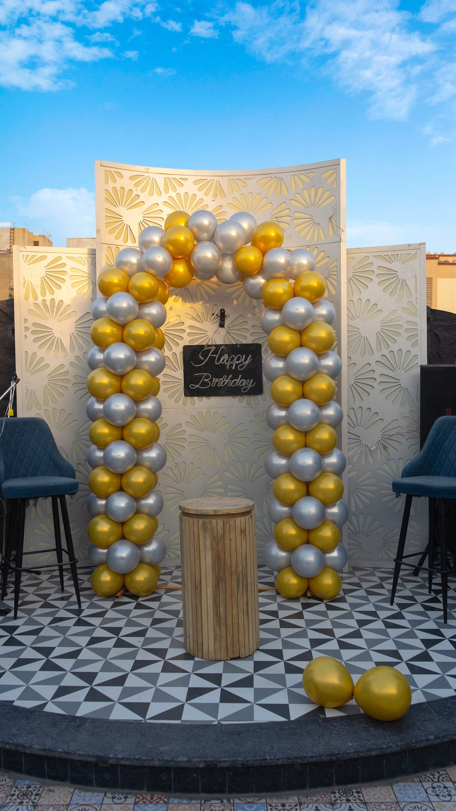 A table set for a celebration, balloons arched behind it